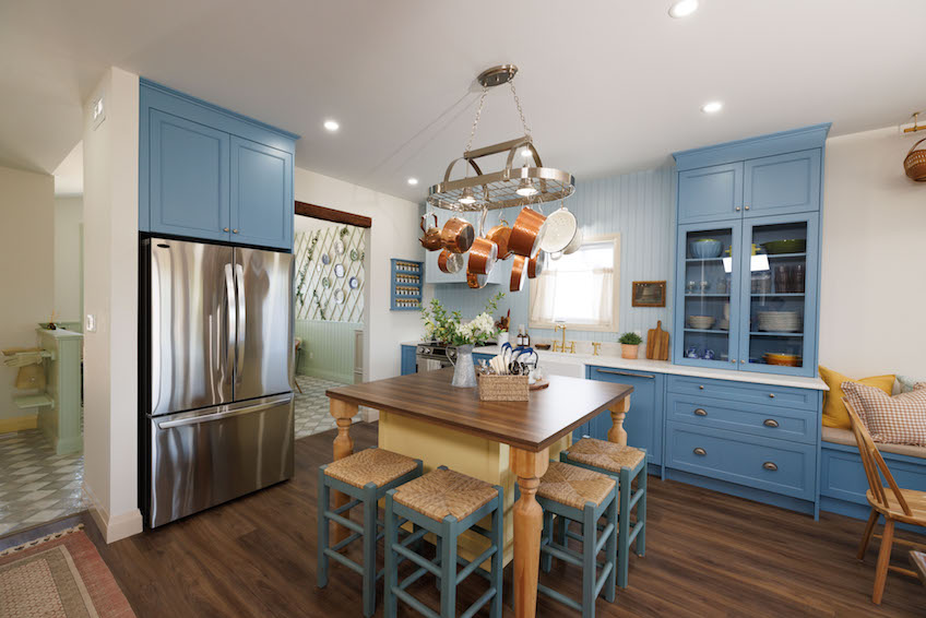 Blue kitchen with wood island and hanging pots and pans