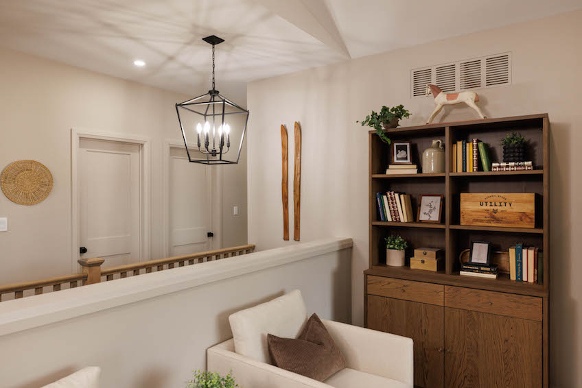Living room with shelves and staircase behind half wall